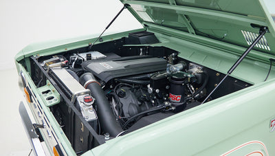 Side view of engine bay revealing radiator, hoses, and power steering components in a light green painted vehicle
