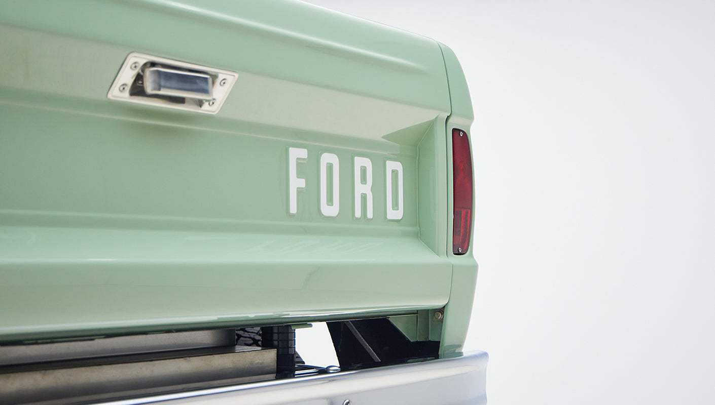 Rear three-quarter view of classic light green Ford Bronco with off-road tires and white steel wheels