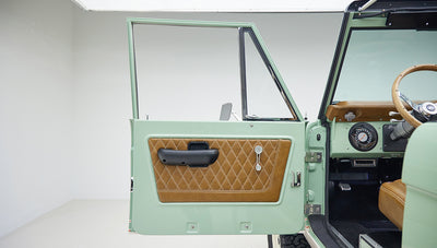 Open door of Classic Ford Bronco with porcelain green paint and tan leather quilted door panel.