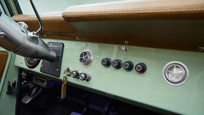 Dashboard controls and air vents of Classic Ford Bronco with porcelain green trim and tan leather accents.