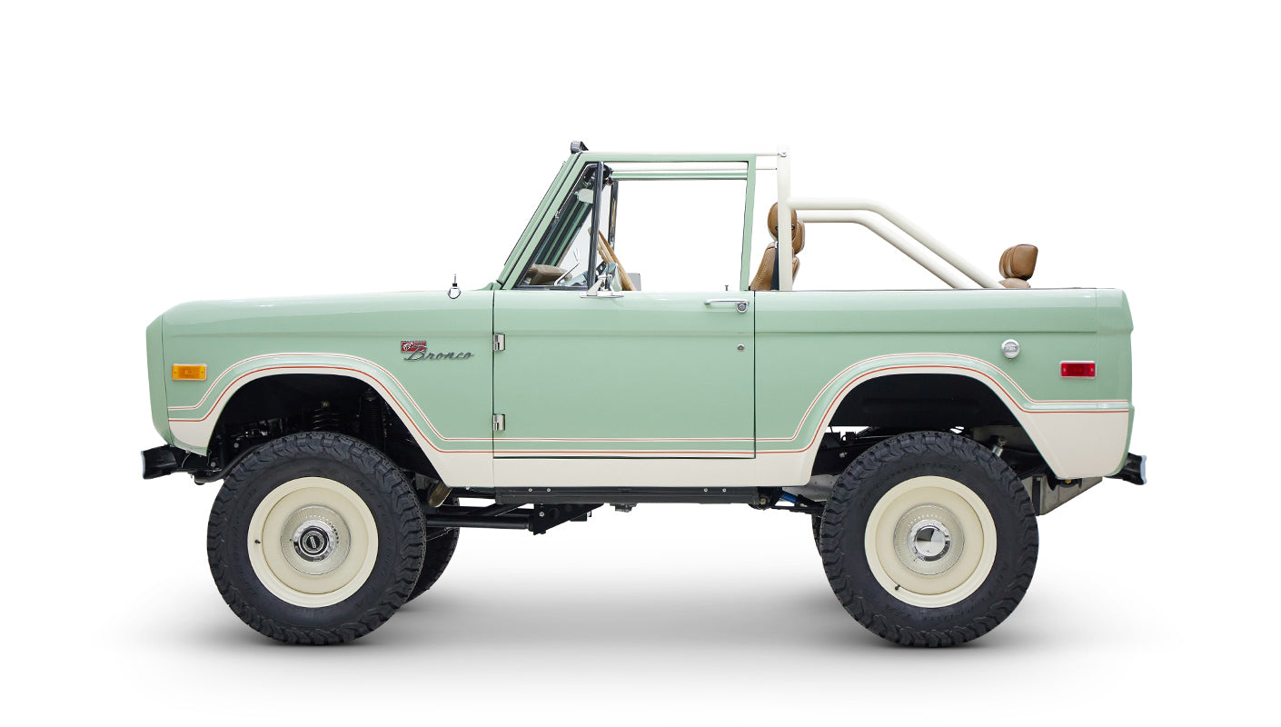 Side view of Classic Ford Bronco in porcelain green with tan seats on white background