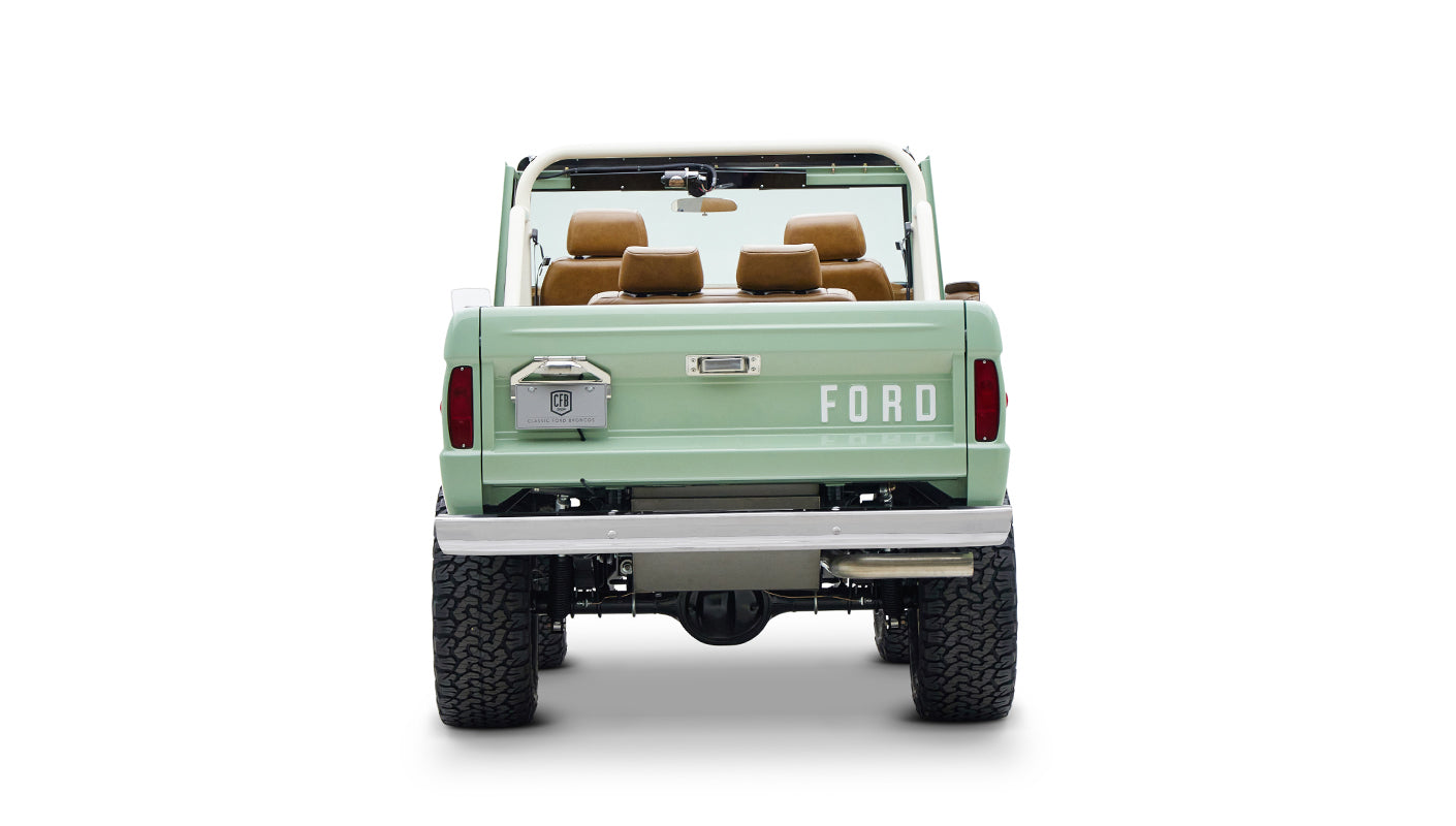 Rear view of Classic Ford Bronco in porcelain green with tan seats on white background
