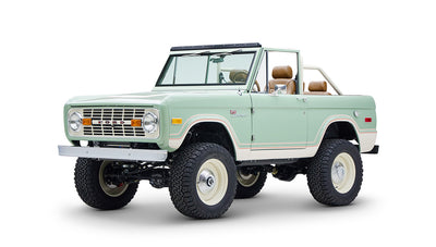 Front-side angle of mint green and cream Classic Ford Bronco with white rims and lifted suspension