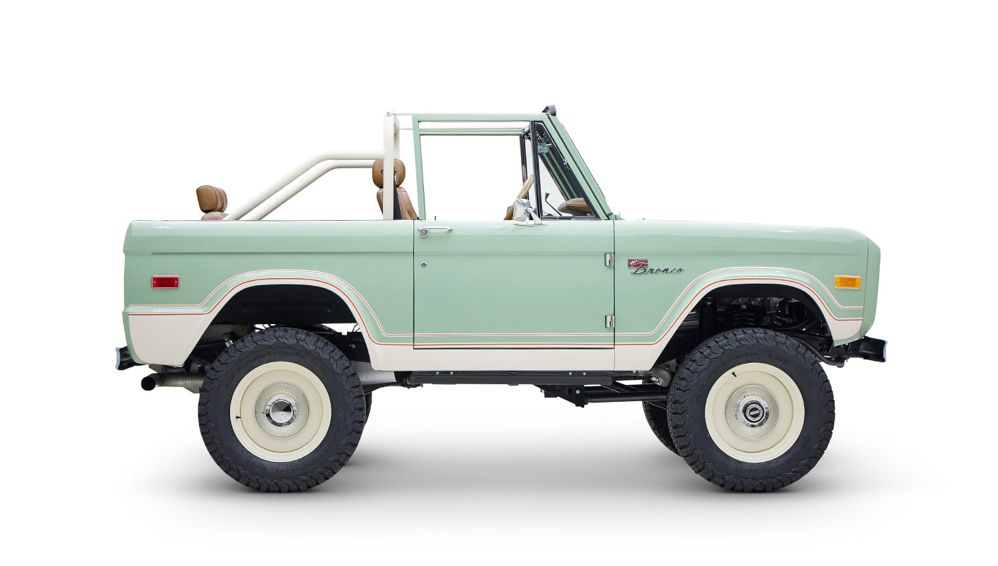 Side view of Classic Ford Bronco in porcelain green with tan seats on white background
