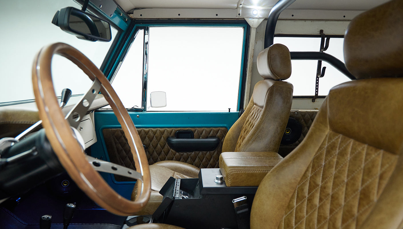 Classic Ford Bronco cabin view with brown leather seats and wooden steering wheel