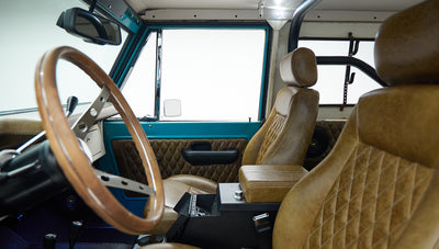 Classic Ford Bronco cabin view with brown leather seats and wooden steering wheel