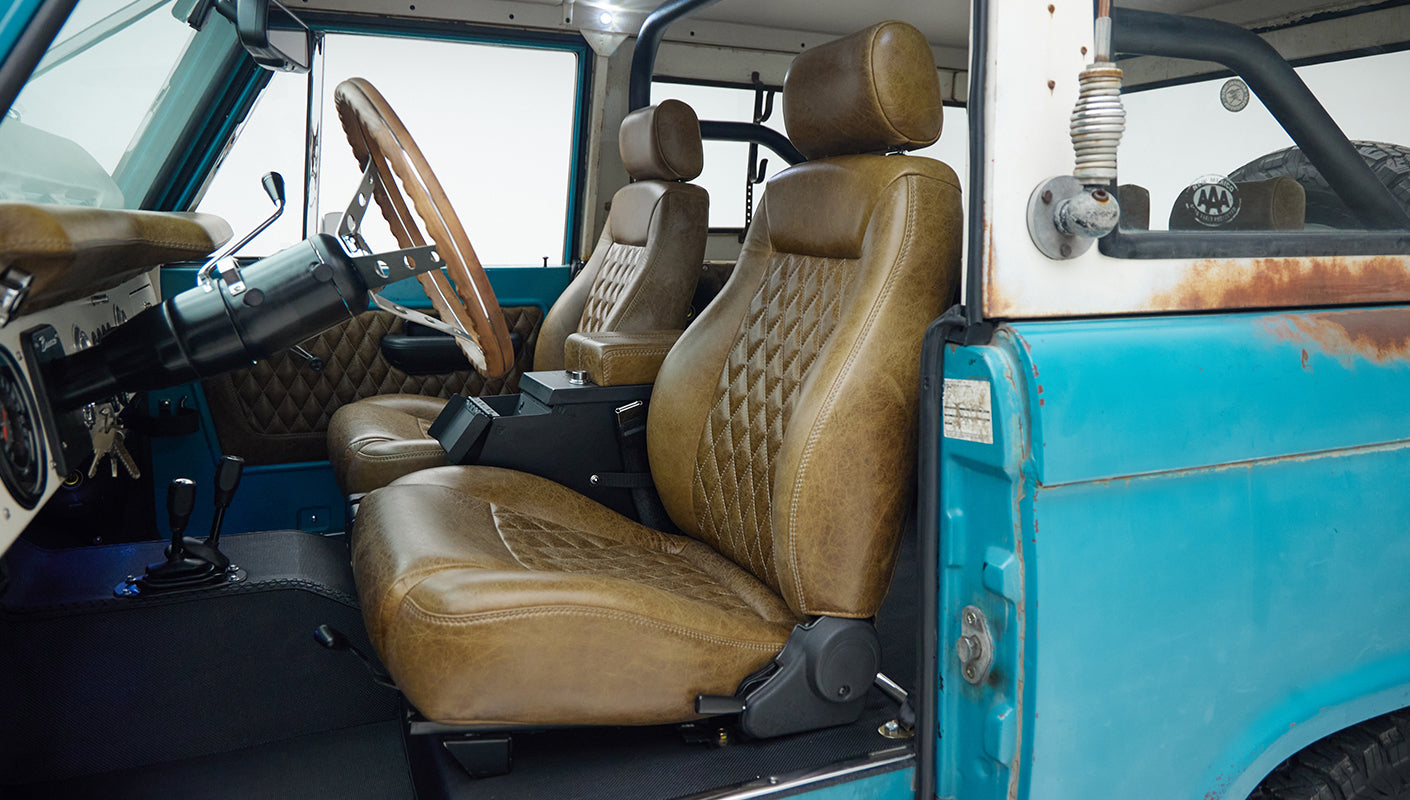 Classic Ford Bronco interior with brown leather seats and turquoise door panel