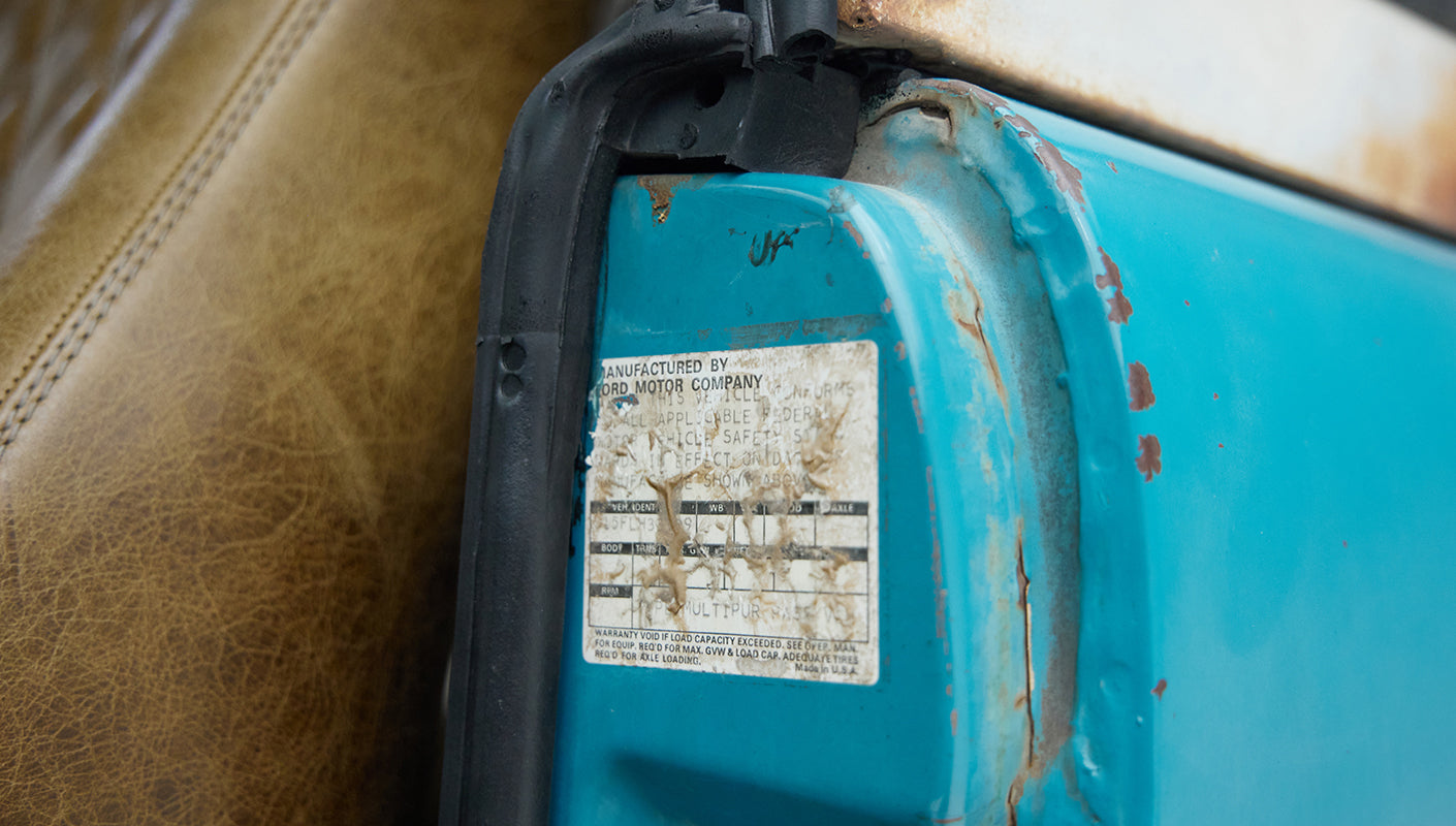 Worn safety instruction sticker inside door frame of turquoise Classic Ford Bronco with leather seats