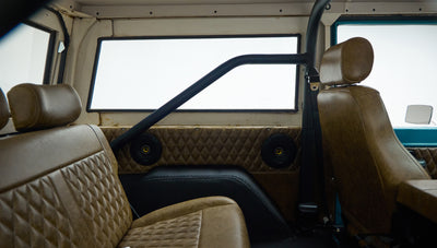 Classic Ford Bronco rear side view showing both front and rear brown leather seats and roll cage
