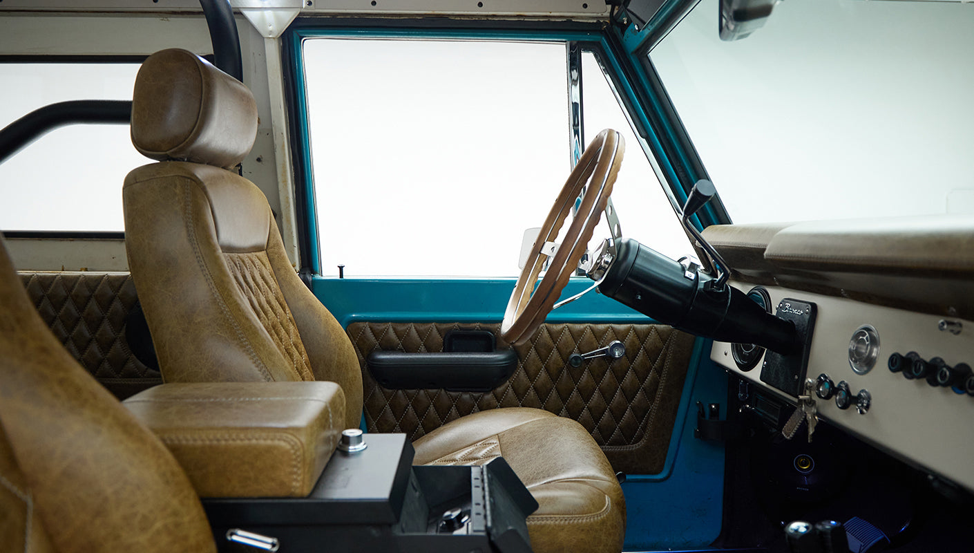 Classic Ford Bronco interior focusing on brown leather seats, door panel, and dashboard