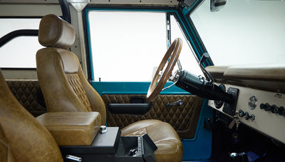 Classic Ford Bronco interior focusing on brown leather seats, door panel, and dashboard