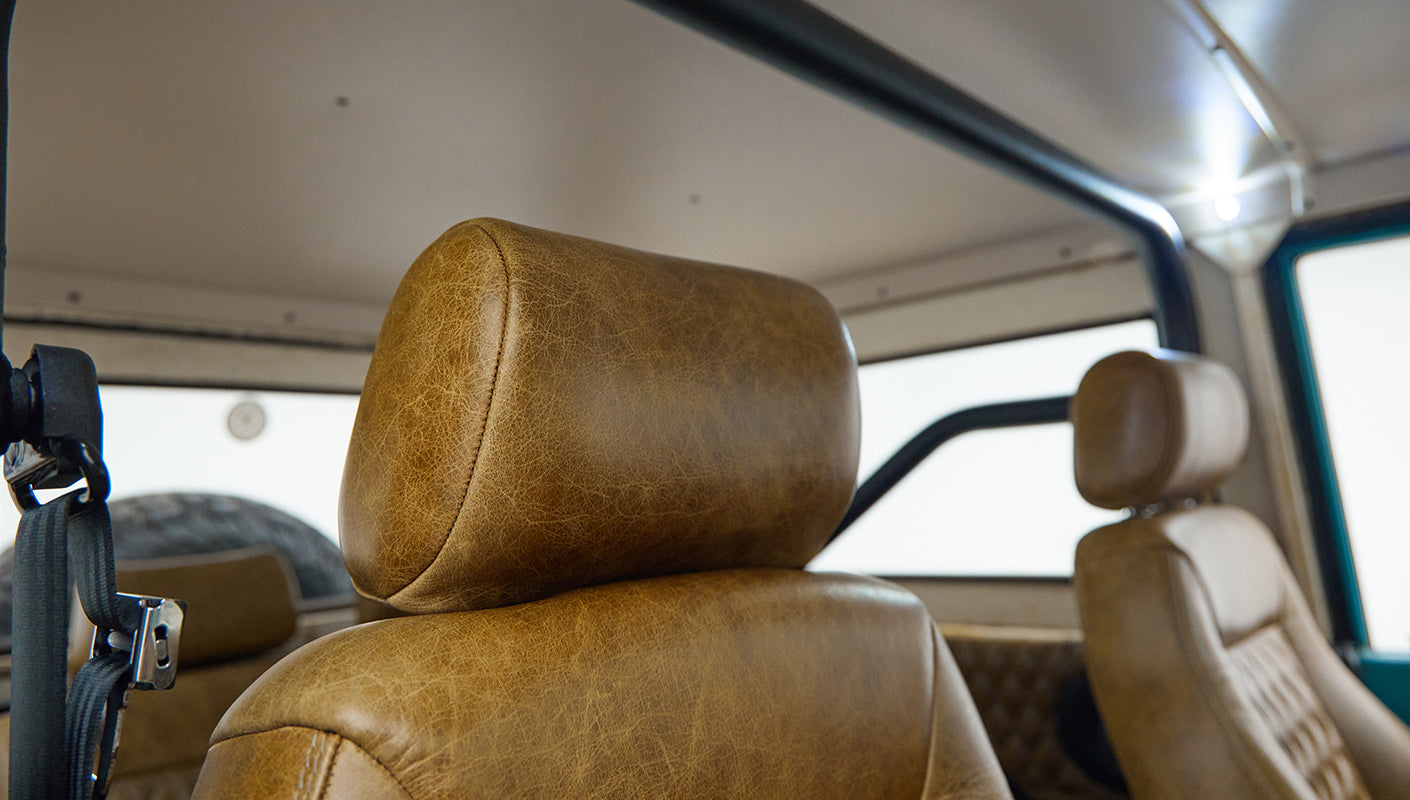Brown leather headrests and classic window with tire visible inside Classic Ford Bronco