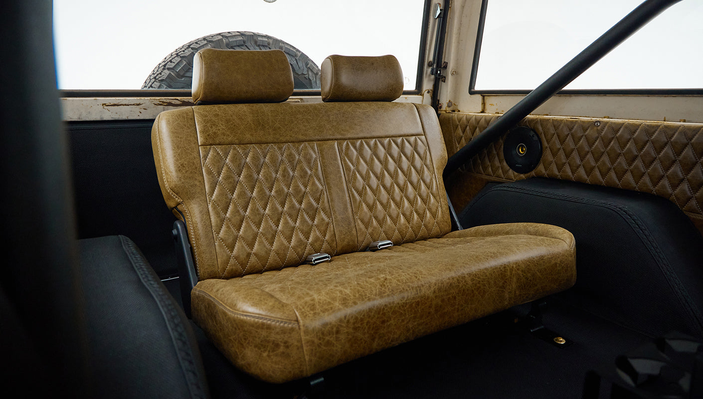Classic Ford Bronco rear bench seat and roll cage visible inside the vehicle