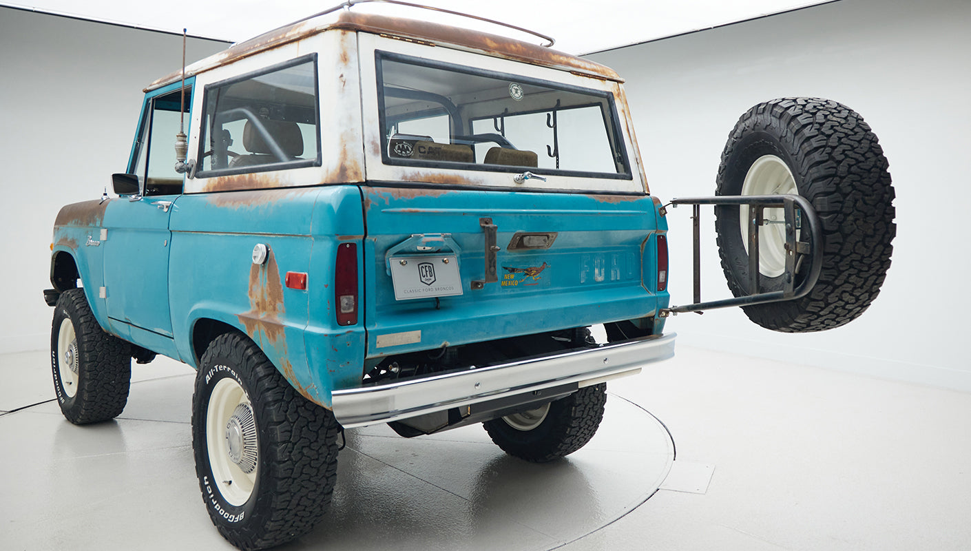 Rear quarter view of Classic Ford Bronco in turquoise patina with mounted spare tire and CFB Series plate