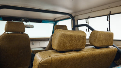 Rear seats and roll cage visible through interior of Classic Ford Bronco with tan leather upholstery