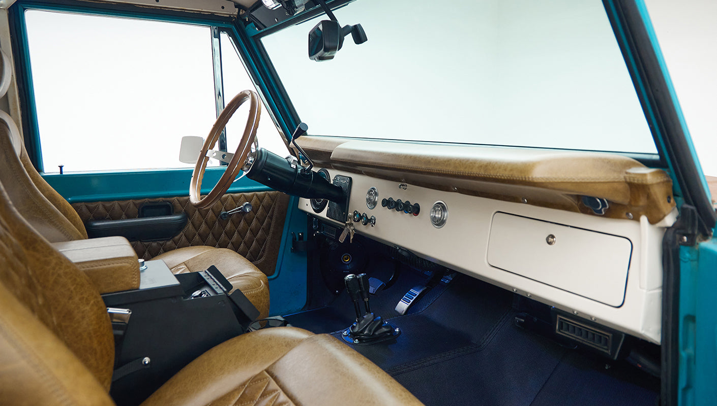 Tan leather front seats and dashboard area with gear shifters inside Classic Ford Bronco