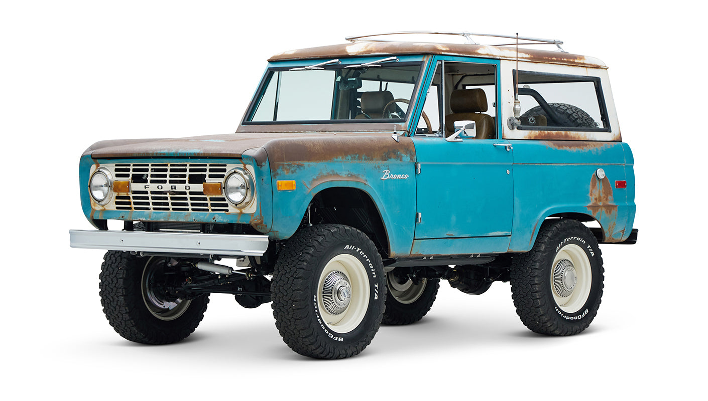 Three-quarter front view of a weathered turquoise Classic Ford Bronco with rust spots on body.