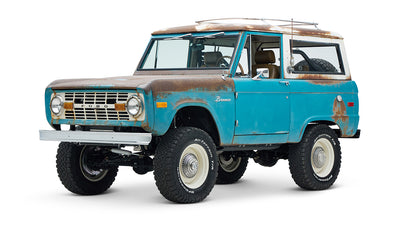 Three-quarter front view of a weathered turquoise Classic Ford Bronco with rust spots on body.