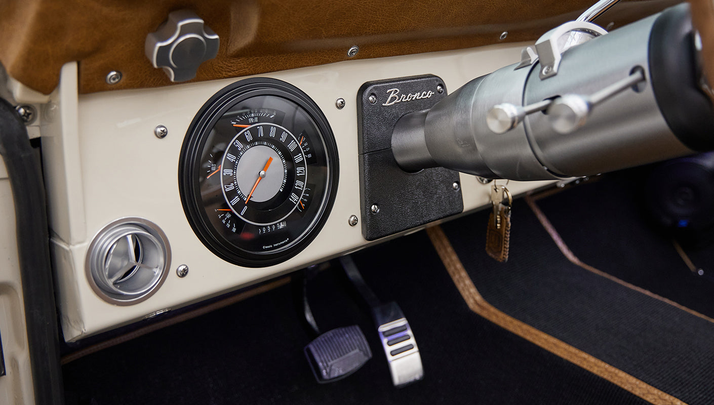 Classic Ford Bronco dashboard featuring speedometer, pedals, and part of steering column