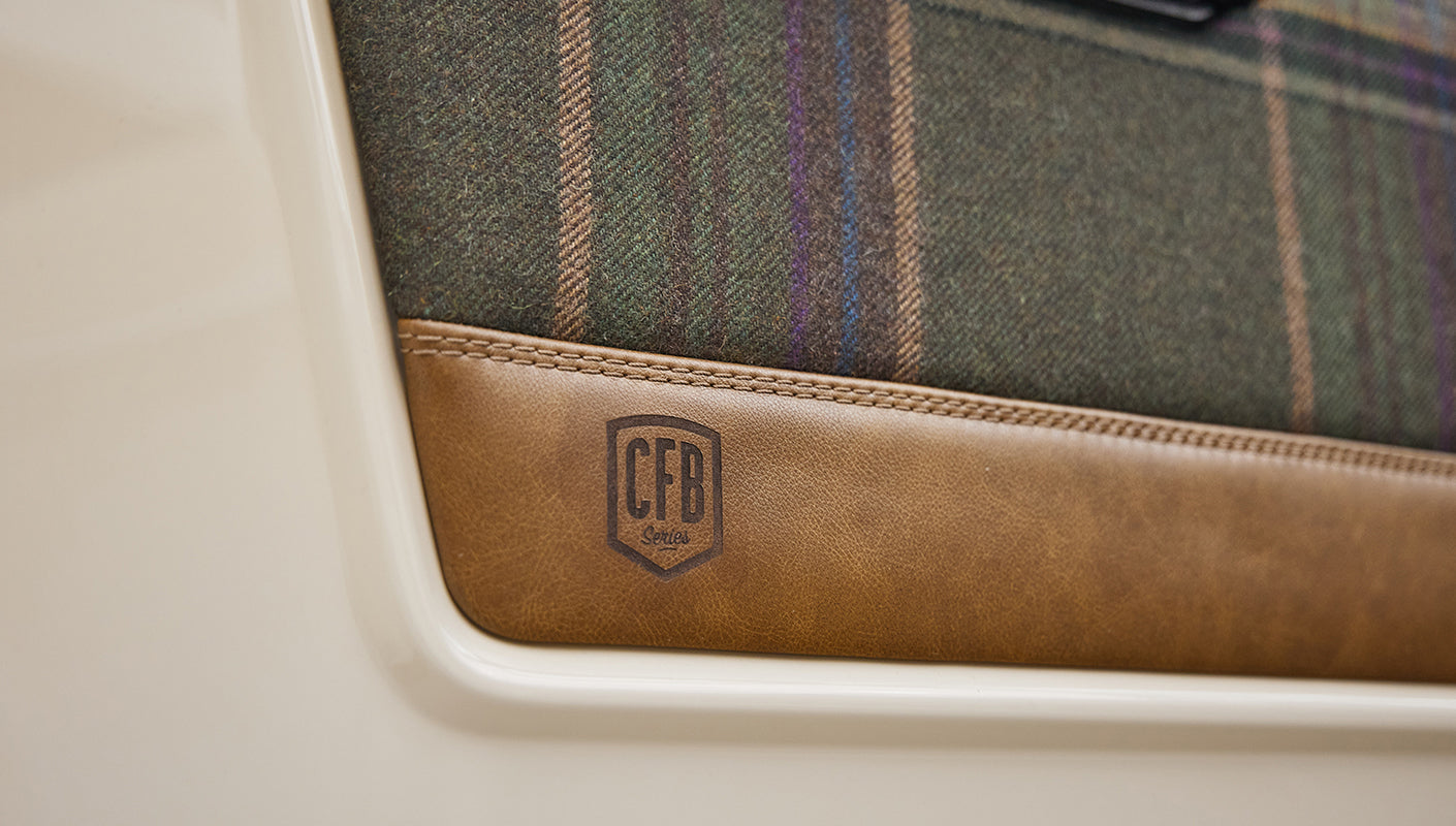 Close-up detail of CFB Series logo on leather and plaid driver door panel of Classic Ford Bronco