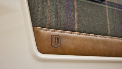 Close-up detail of CFB Series logo on leather and plaid driver door panel of Classic Ford Bronco