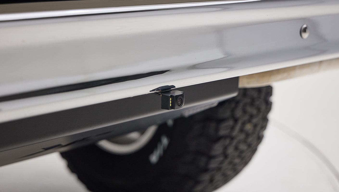 Rear backup camera mounted under rear bumper of Classic Ford Bronco with off-road tire visible