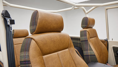 Two front seats of Classic Ford Bronco with brown leather and plaid fabric upholstery