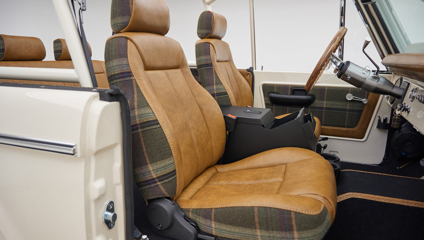 Driver and passenger seats inside Classic Ford Bronco with brown leather and plaid fabric