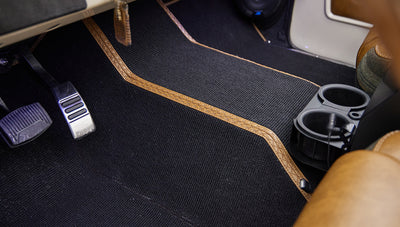 Floor area of Classic Ford Bronco interior with black carpet and brown trim