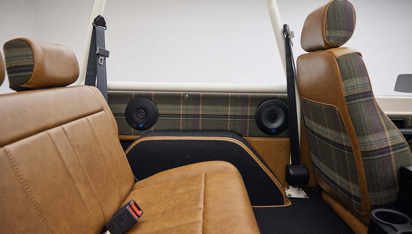 Backseat area of Classic Ford Bronco featuring brown leather seats and plaid fabric details