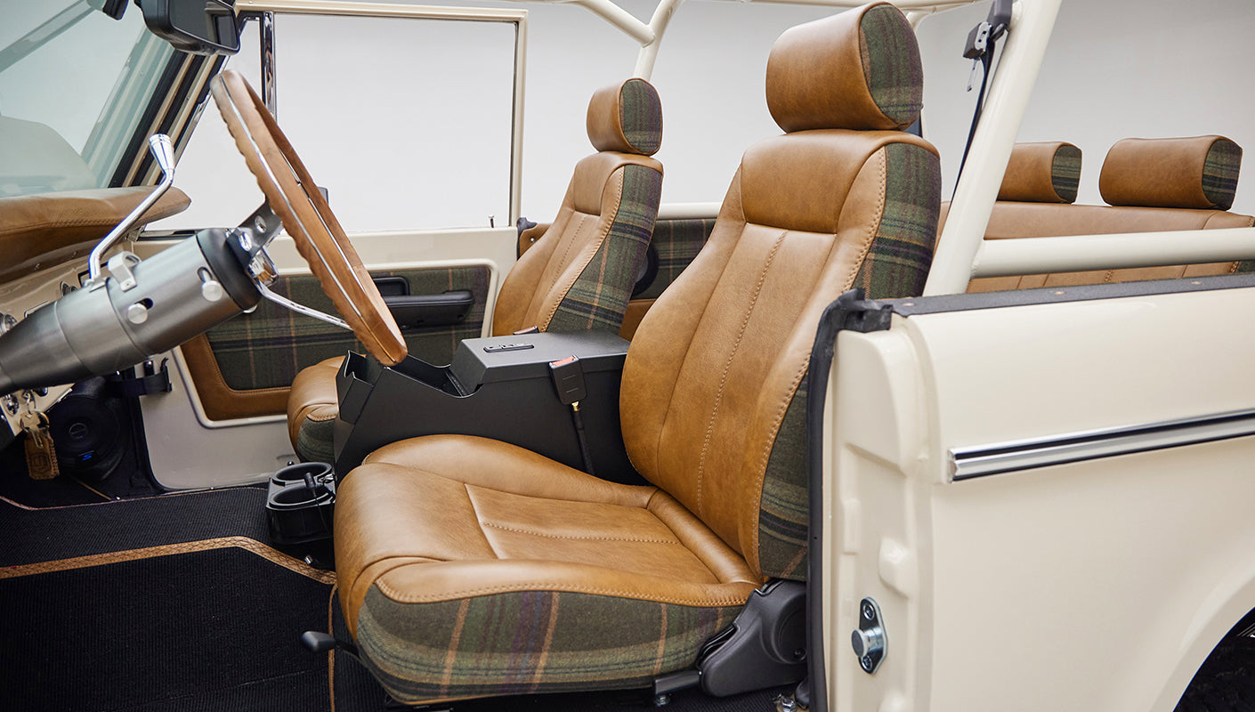 Interior front seats of a Classic Ford Bronco in brown leather with plaid fabric accents