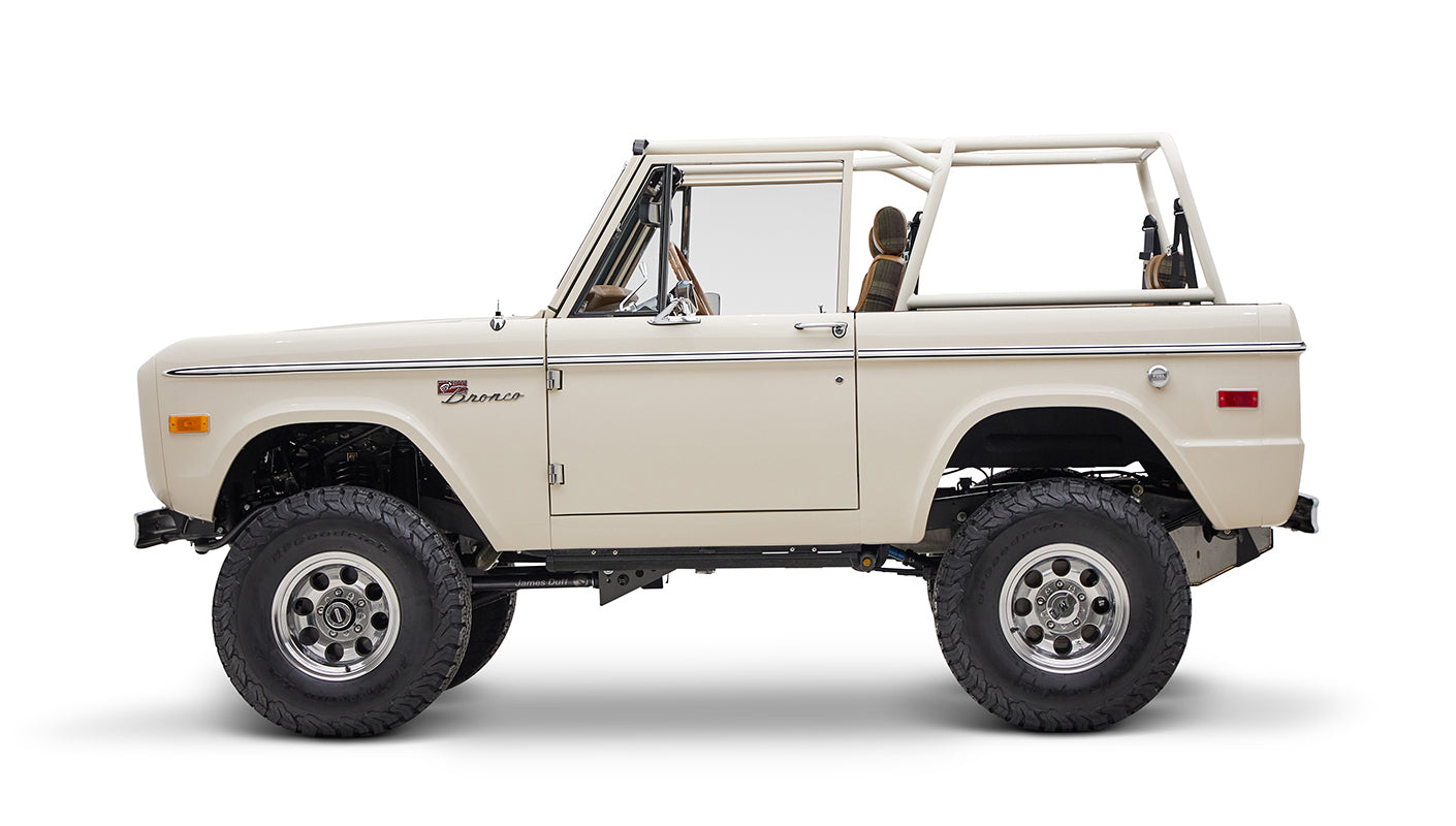 Classic Ford Bronco cream color in side view with focus on driver side on white background
