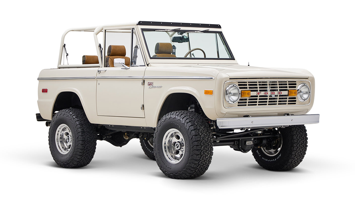 Classic Ford Bronco cream color with brown seats and open roof shown from front-left angle on white background