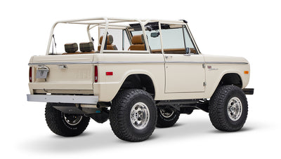 Classic Ford Bronco cream color with brown and plaid seats and open roof shown from back-right angle on white background