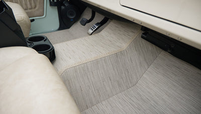 Floor board area with beige floor mats and black cup holder near front seats in Classic Ford Bronco
