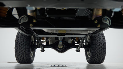 Underbody view of rear axle, suspension, and drivetrain components of Classic Ford Bronco with tires