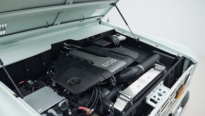 Clean engine bay of Classic Ford Bronco showing black engine cover labeled 5.0 with surrounding components