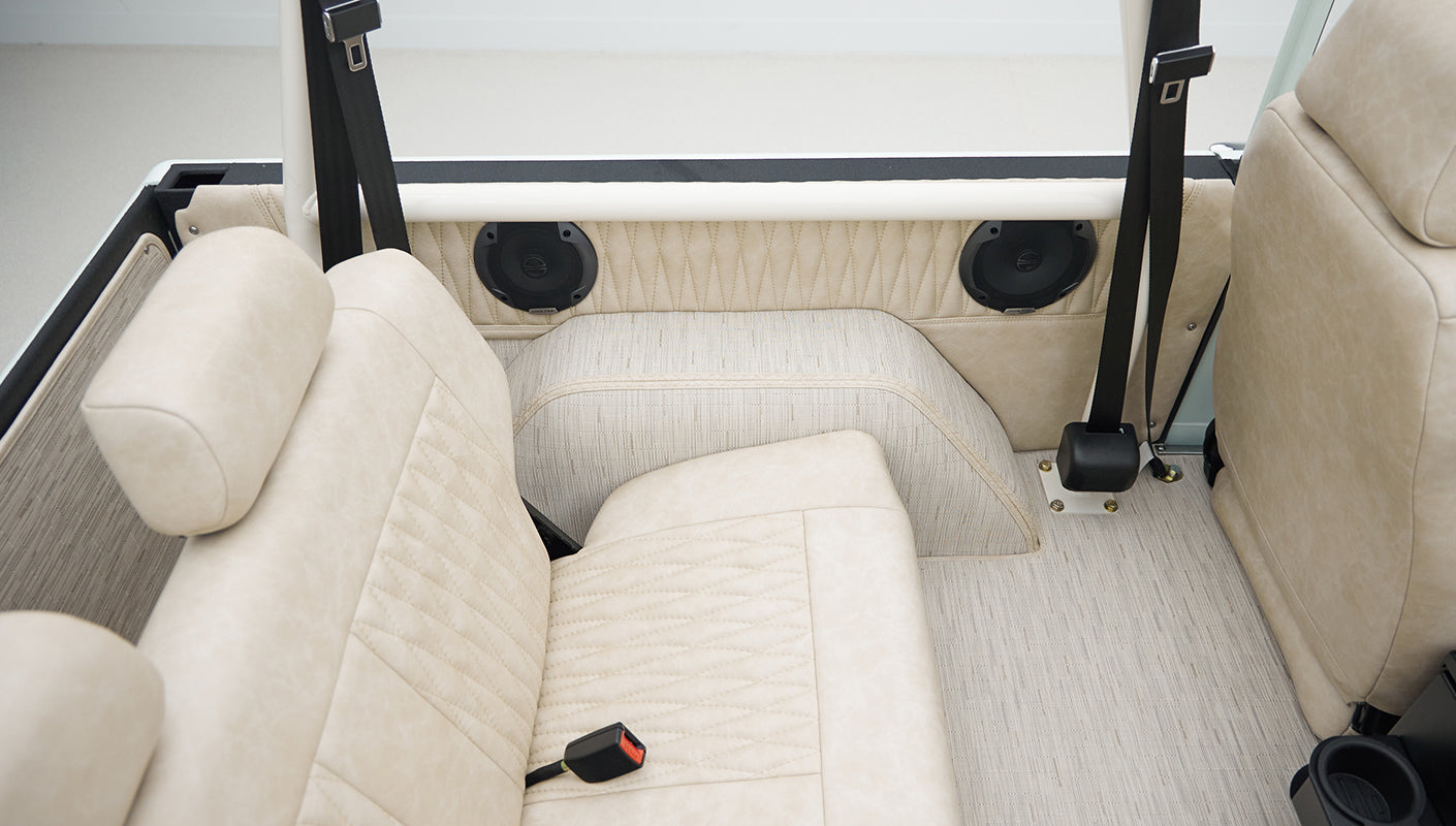 Detail of black Alpine speaker embedded in beige quilted upholstery of Classic Ford Bronco rear interior panel