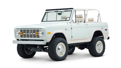 Three-quarter front view of white Classic Ford Bronco 1974 Diamondblue Coyote Series with off-road tires