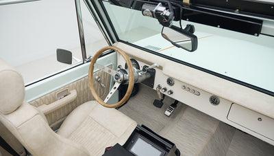 Rear seating area of Classic Ford Bronco with beige quilted upholstery and speakers on side panels