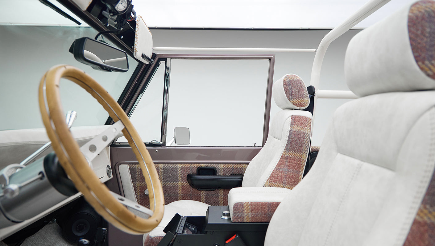 Interior view of Classic Ford Bronco front seats with white and plaid upholstery and wood steering wheel