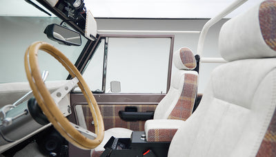 Interior view of Classic Ford Bronco front seats with white and plaid upholstery and wood steering wheel