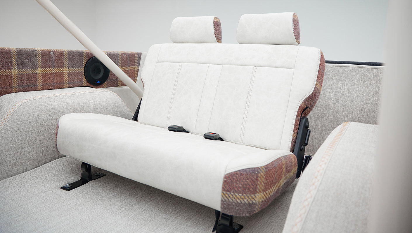 Rear bench seat of Classic Ford Bronco with white and plaid upholstery and side panel speakers