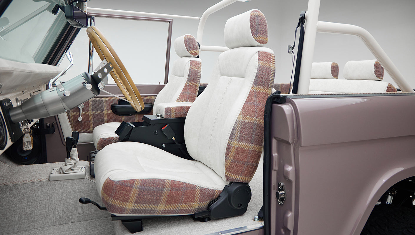 Side profile of Classic Ford Bronco interior front seats with plaid and white upholstery and open door