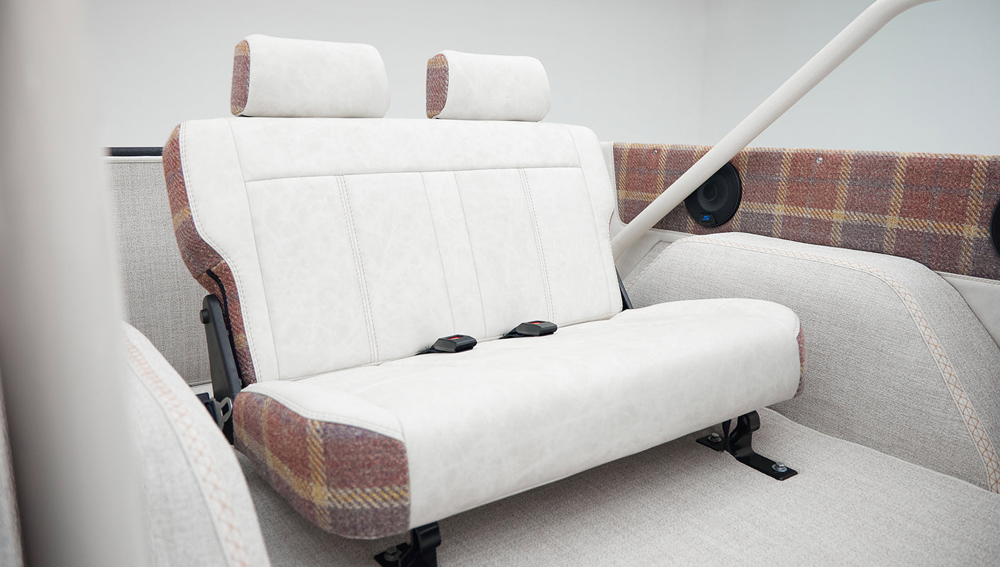 Rear bench seat of Classic Ford Bronco with white and plaid upholstery seen from a different angle