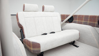 Rear bench seat of Classic Ford Bronco with white and plaid upholstery seen from a different angle
