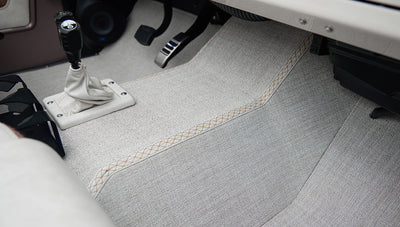 Classic Ford Bronco carpeted floor showing area under center console with gear shift levers and pedals.