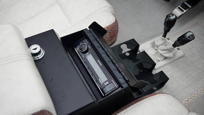 Center console of Classic Ford Bronco with open compartment housing a Kenwood stereo system and cup holders.