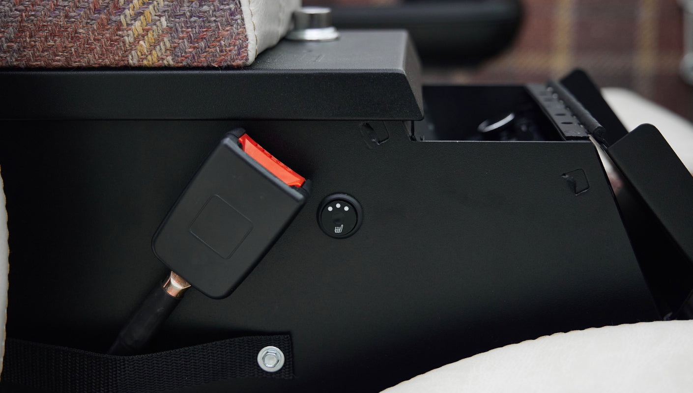 Seatbelt buckle and a switch with a heated seat icon on the side of a car seat, likely Classic Ford Bronco interior.
