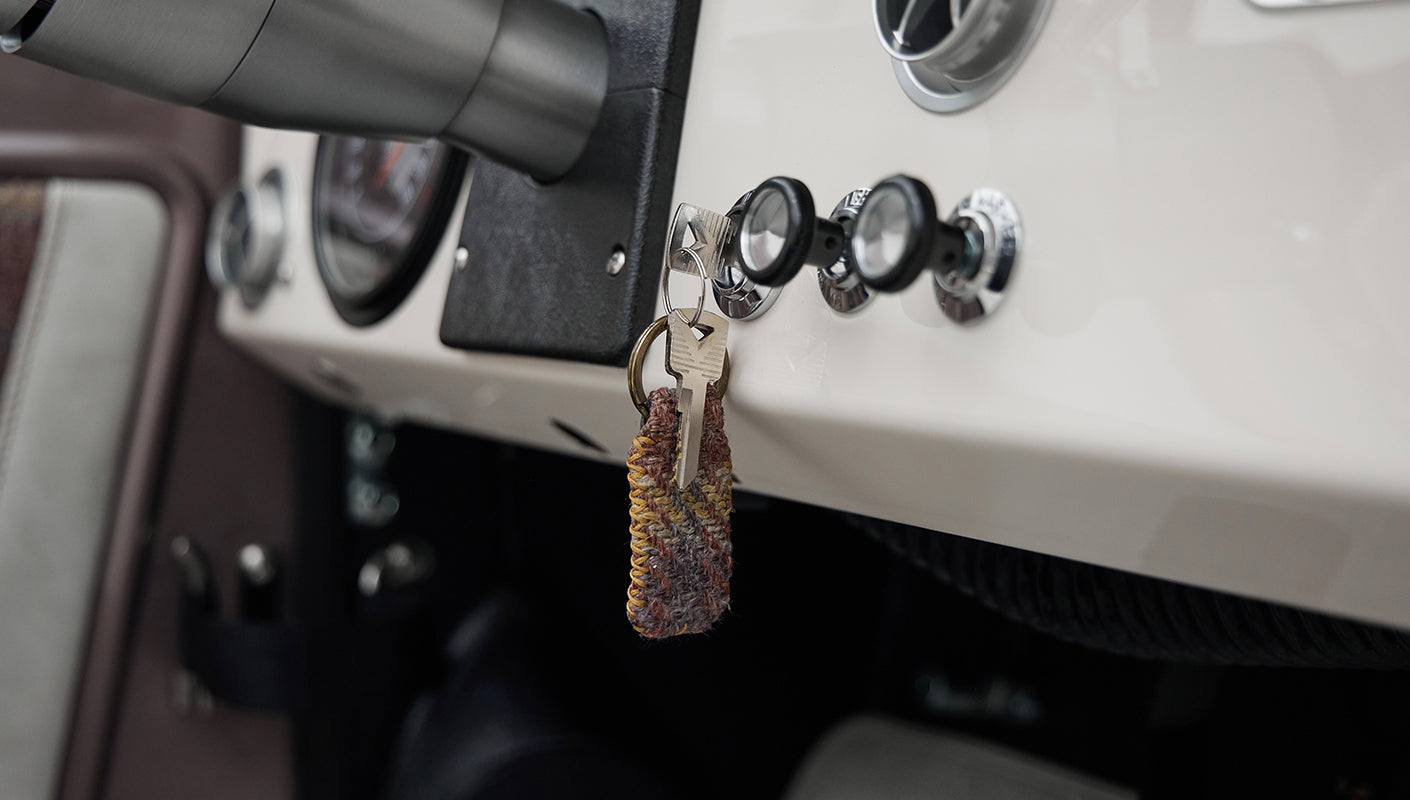 Classic Ford Bronco dashboard close-up showing another ignition key with a knitted fabric keychain.